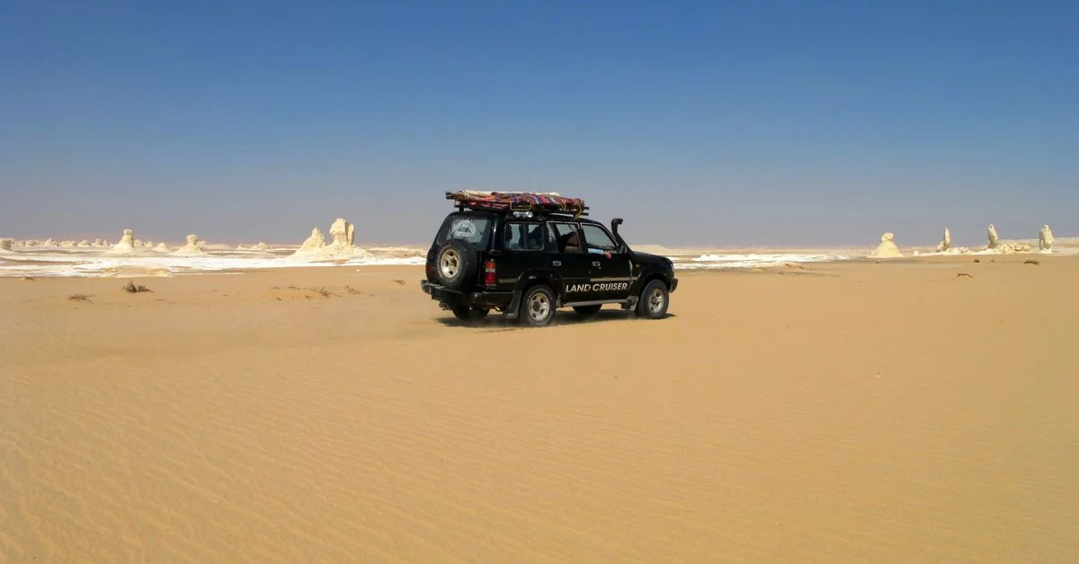 Explorez le vaste Désert Blanc égyptien avec un véhicule 4x4 sous un ciel bleu dégagé.