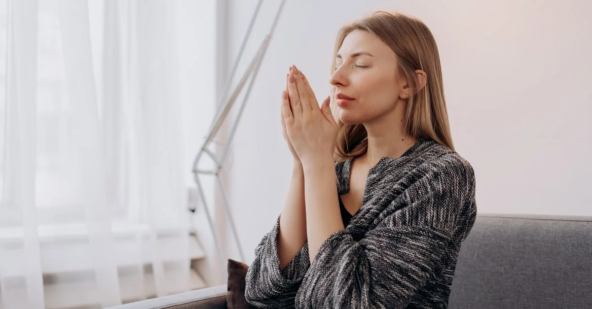 Une femme médite paisiblement à l'intérieur, recherchant la détente et la paix intérieure à travers des pratiques de pleine conscience.