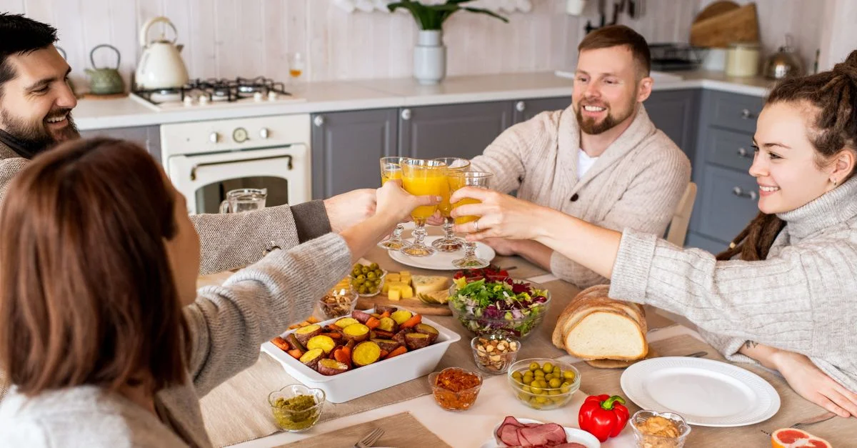 Groupe d'amis profitant d'un repas joyeux ensemble à la maison, partageant rires et nourriture.