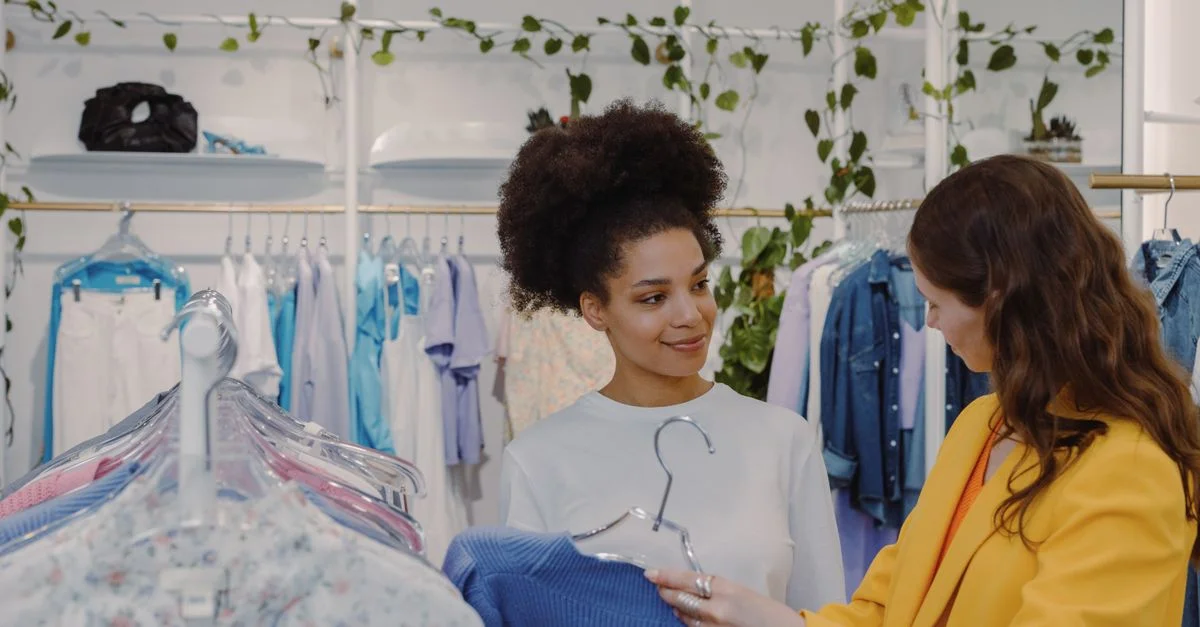 Deux femmes faisant du shopping dans un magasin de vêtements moderne et élégant avec une ambiance conviviale.