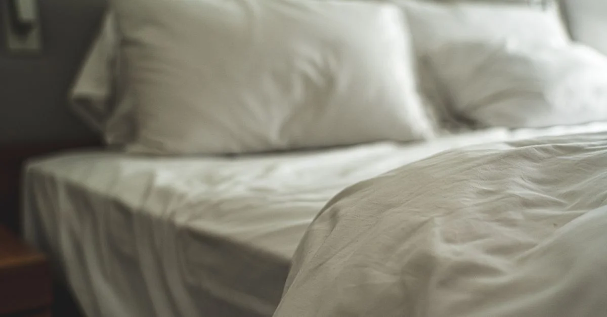 Linge de lit blanc élégant avec des oreillers doux créant une atmosphère chaleureuse et accueillante.